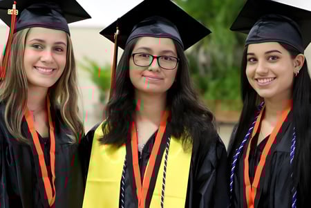Tres alumnas de RGS Surrey Hills en ropa de graduación están juntas frente a un fondo verde.