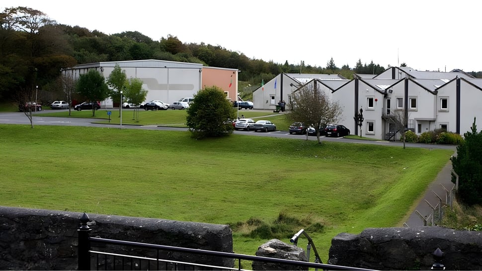 Un campo verde frente a edificios residenciales y un edificio industrial más grande en el terreno del Rice College.