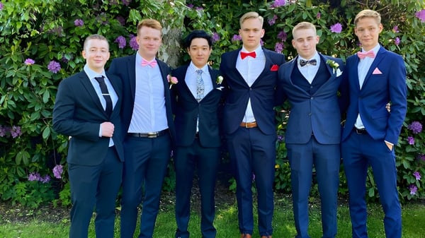 Un grupo de estudiantes del Rice College está en un jardín verde con flores en flor.