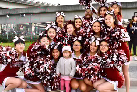 Un grupo de animadoras en rojo y blanco posando afuera en el terreno de la Richmond Secondary School.