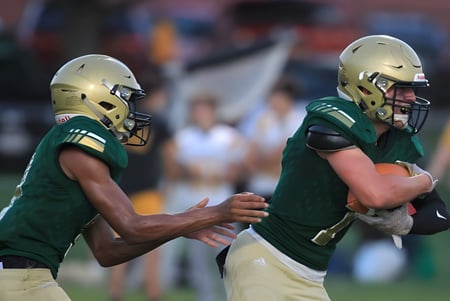 Dos jugadores de fútbol americano en camisetas verdes se dan la mano en el campo de Ridgemont High School.