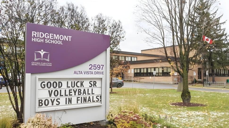 La vista exterior de Ridgemont High School con un cartel de felicitación para el equipo de voleibol masculino en la final.