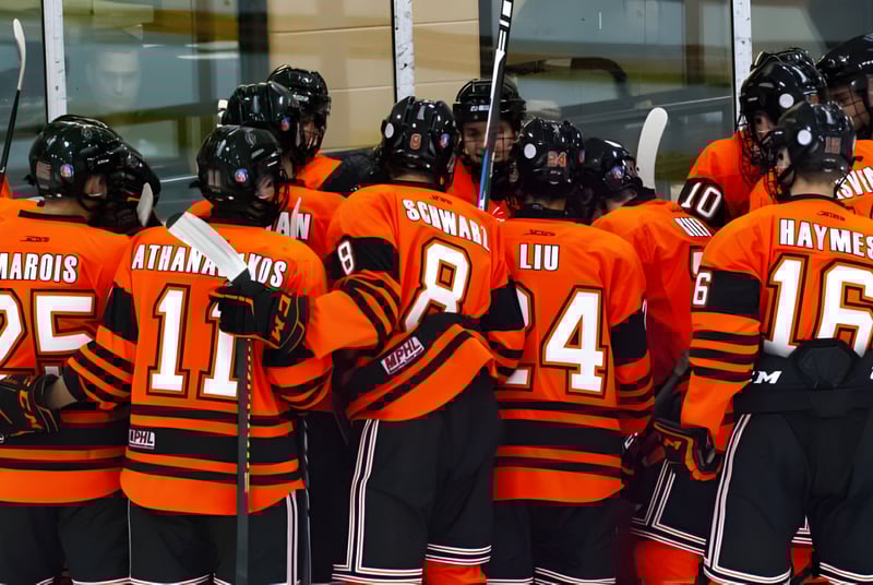 Un grupo de jugadores de hockey en camisetas naranjas está junto a un edificio en el campus del Ridley College.