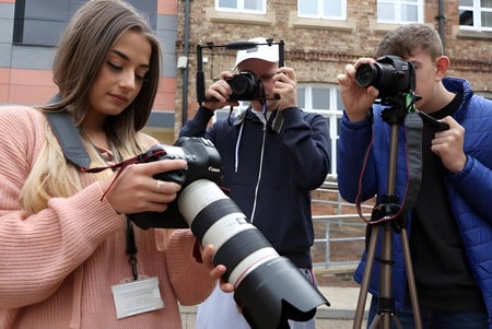 Un grupo de estudiantes de la Ringwood School fotografía con cámaras frente a edificios de ladrillo en la ciudad.