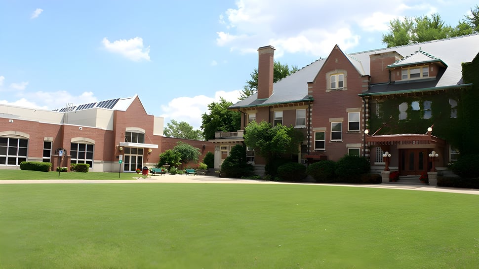 El edificio principal del Rivermont Collegiate está rodeado de un cuidado césped verde y árboles.