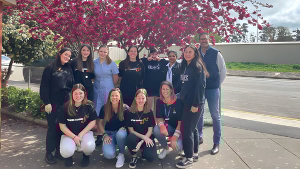 Un grupo de jóvenes mujeres se encuentra frente a un árbol en flor en el terreno de la Riverton and District High School.