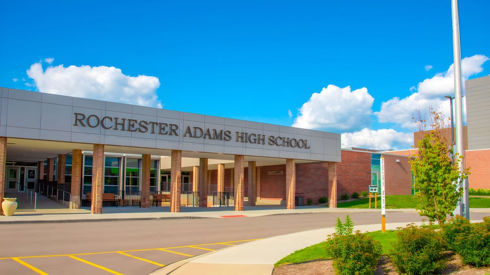 El gran edificio de ladrillo de Rochester Community Schools bajo un cielo azul con nubes blancas.