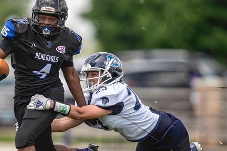 Dos jugadores de fútbol americano de la Rockford Lutheran School luchan en el campo por el balón.