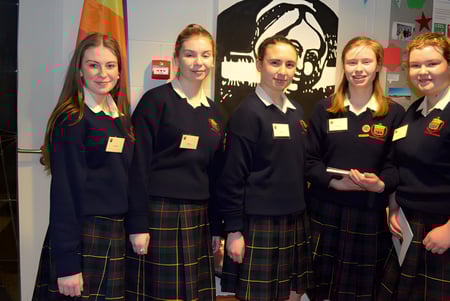 Cinco alumnas en uniformes escolares están frente a un colorido mural en el campus de la Rockford Manor School.