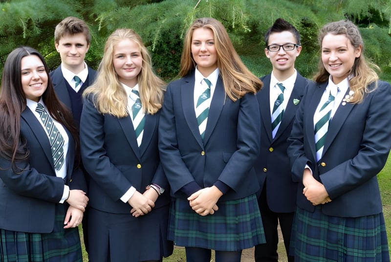 Un grupo de estudiantes de la Rockport School está de pie juntos en un área cubierta de hierba con árboles de fondo.