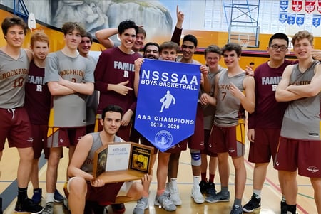 Un grupo de jugadores de baloncesto de la Rockridge Secondary School sostiene orgullosamente un banner de campeonato en el gimnasio.