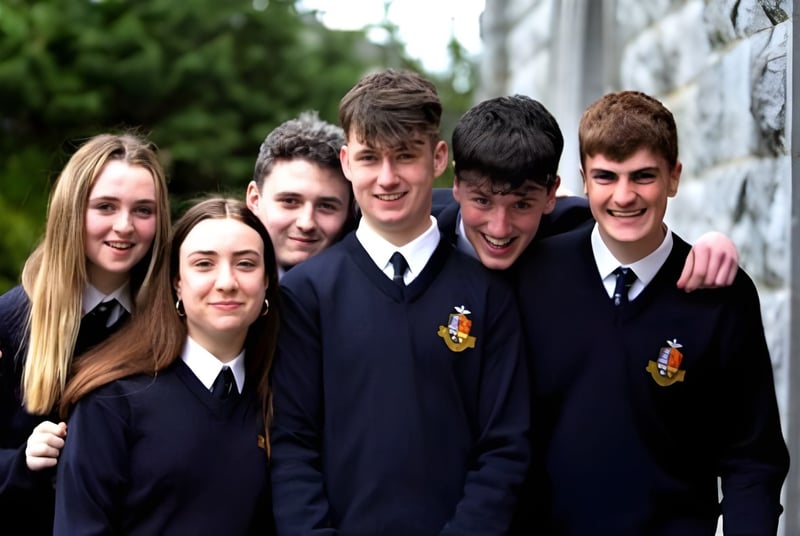 Un grupo de estudiantes del Rockwell College está junto a una pared de piedra con plantas verdes.