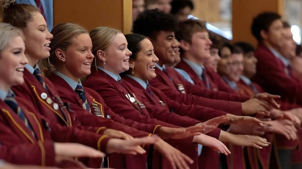 Un grupo de estudiantes con togas rojas participa en una ceremonia formal en el Roncalli College.