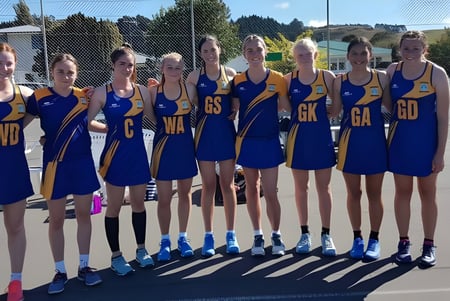 Un grupo de jóvenes jugadoras de netball está en la cancha en el campus del Roncalli College.