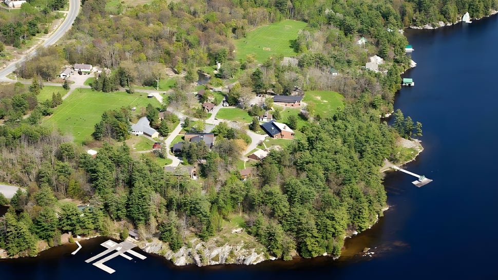 Un paisaje boscoso con un camino sinuoso y un lago al fondo cerca de Rosseau Lake College.