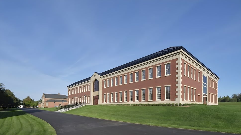 El edificio de ladrillo de varios pisos de la Rothesay Netherwood School se encuentra en un campo bajo un cielo despejado.