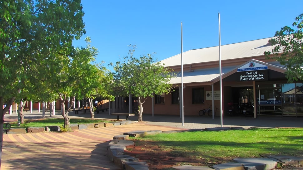 El moderno edificio de entrada de la Roxby Downs Area School está rodeado de plantas verdes y un camino pavimentado.