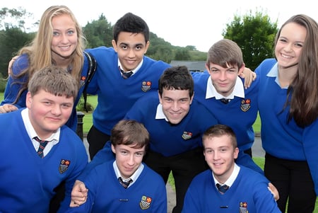 Un grupo de estudiantes de la Royal and Prior Comprehensive School posan juntos afuera en un prado frente a los árboles.