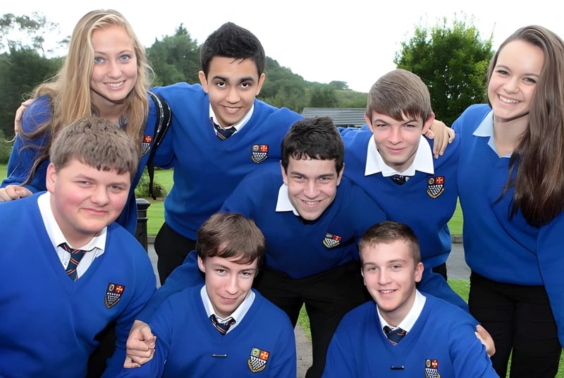 Un grupo de estudiantes de la Royal and Prior Comprehensive School posan juntos afuera en un prado frente a los árboles.