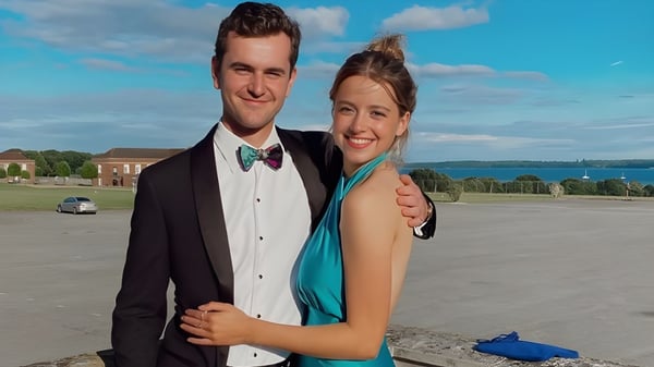 Una pareja está frente a un paisaje con agua y edificios en el terreno de la Royal Hospital School.