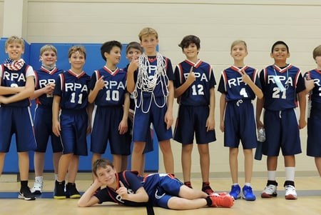 Un grupo de estudiantes de la Royal Palm Academy posa en sus uniformes de baloncesto azules en un gimnasio.