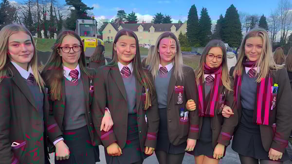 Un grupo de estudiantes en uniformes similares a los de Hogwarts está frente a un pintoresco fondo en el campus de la Royal School Dungannon.