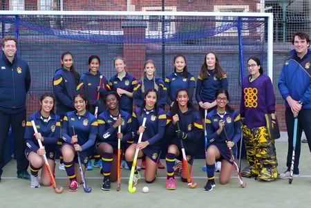Un grupo de jóvenes deportistas posan en el campo de deportes de The Royal School Wolverhampton frente a un edificio de ladrillo.