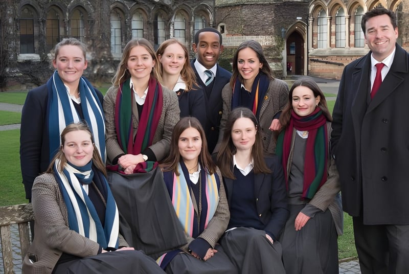 Un grupo de estudiantes de la Rugby School posan frente a un edificio histórico con arquitectura gótica.
