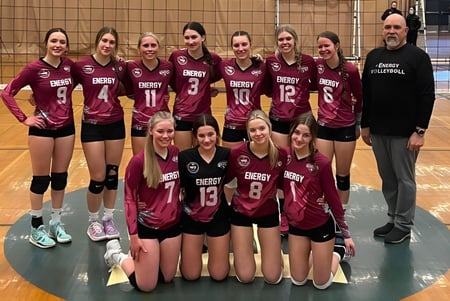 Un grupo de jugadoras de voleibol de la Rutland Senior Secondary School posan junto a su entrenador en el gimnasio.