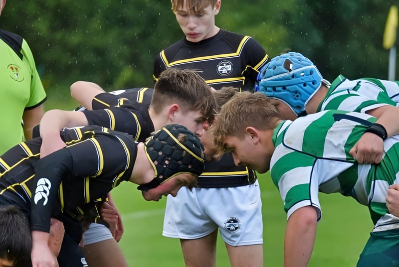 Un grupo de estudiantes que juegan al rugby de la Rydal Penrhos School se puede ver en el scrum en el campo de césped.
