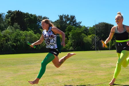 Dos estudiantes corren en un campo de césped con árboles al fondo en el terreno del Sacred Heart Girls' College en New Plymouth.