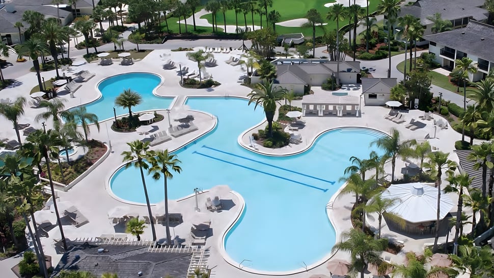 El gran área de la piscina con palmeras y edificios en el terreno de la Saddlebrook Preparatory School.