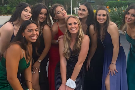 Un grupo de jóvenes mujeres con vestidos coloridos posan afuera en el campus de la Sagemont School.