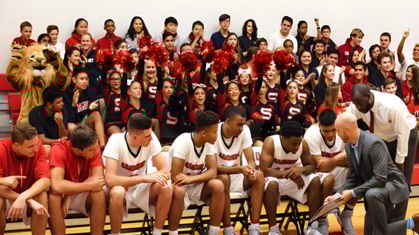 Un grupo de estudiantes de la Sagemont School se reúne en un gimnasio con uniformes rojos y blancos.