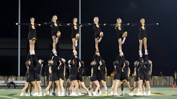 Un grupo de porristas realiza una rutina sincronizada en el campo deportivo de Saint Anthony's High School por la noche.