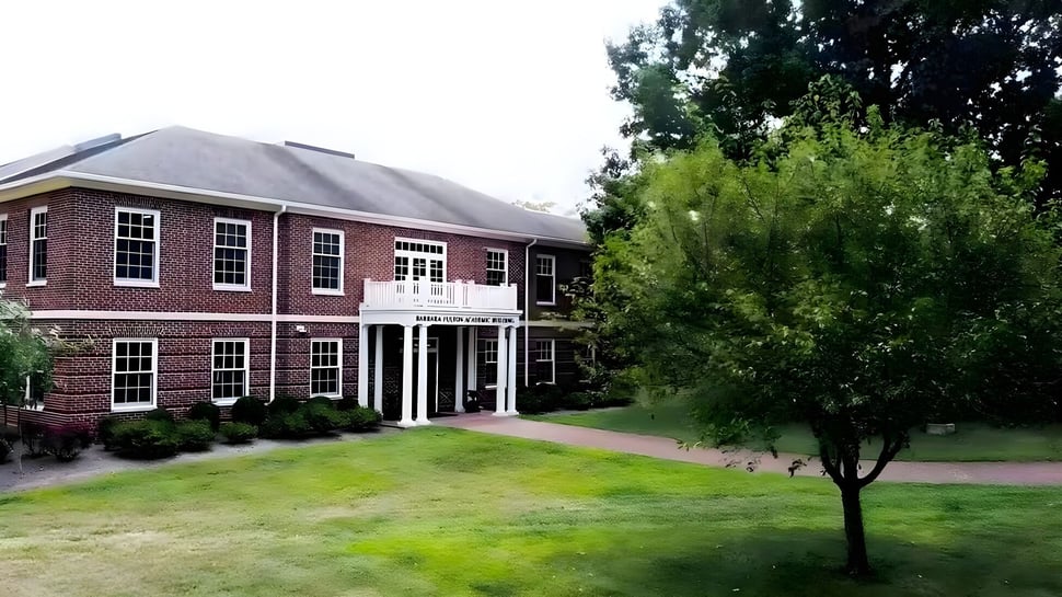 El edificio de ladrillo con una fachada de columnas de la Saint James School se encuentra en un área cubierta de hierba con árboles.