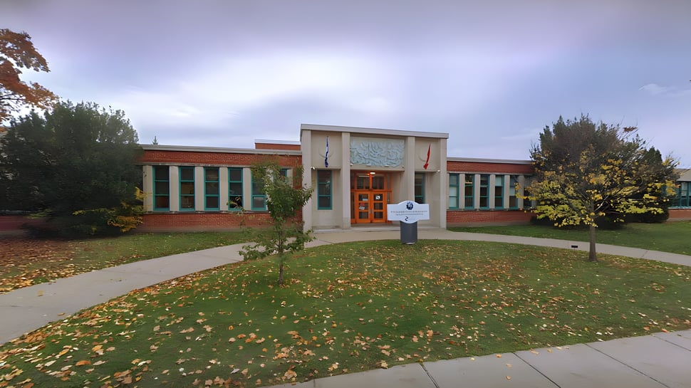 El moderno edificio de ladrillo de la Saint-Lambert International High School con grandes ventanas y césped decorado para el otoño.