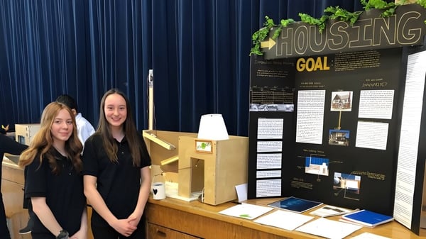 Dos estudiantes de la Saint-Lambert International High School están frente a un panel de información con el título Housing.