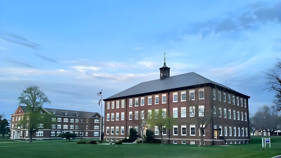 El edificio de ladrillo de varios pisos con torre del reloj en el campus de la Saint Paul Lutheran High School está rodeado de un prado.