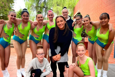 Un grupo de estudiantes en ropa deportiva está frente a un edificio de ladrillo en el terreno de la Salisbury East High School.