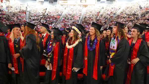 Los graduados de la San Diego State University están juntos en túnicas rojas y negras durante la ceremonia de graduación.