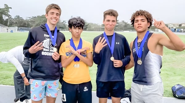 Cuatro niños en ropa deportiva con medallas están en un campo en el San Luis Coastal Unified School District.