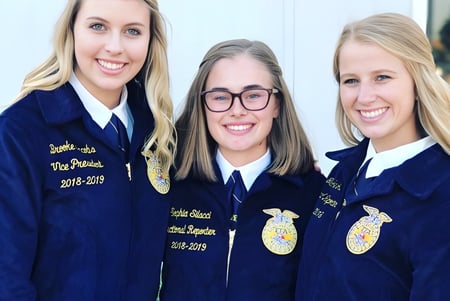 Tres alumnas en chaquetas azules de FFA posan juntas en el exterior de la San Luis Obispo High School.