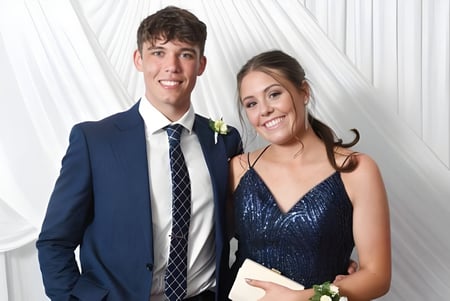 Una joven pareja posa con ropa formal frente a una cortina blanca en el campus del Sancta Maria College.