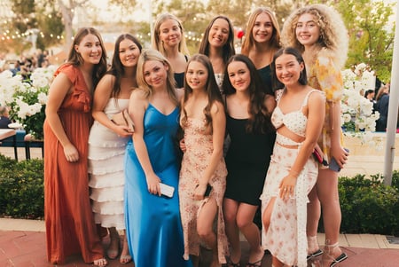 Un grupo de alumnas del Sancta Maria College posan afuera frente a árboles y un camino pavimentado.