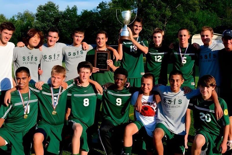 Estudiantes de la Sandy Spring Friends School celebran en el campo de deportes su victoria con un trofeo en la mano.