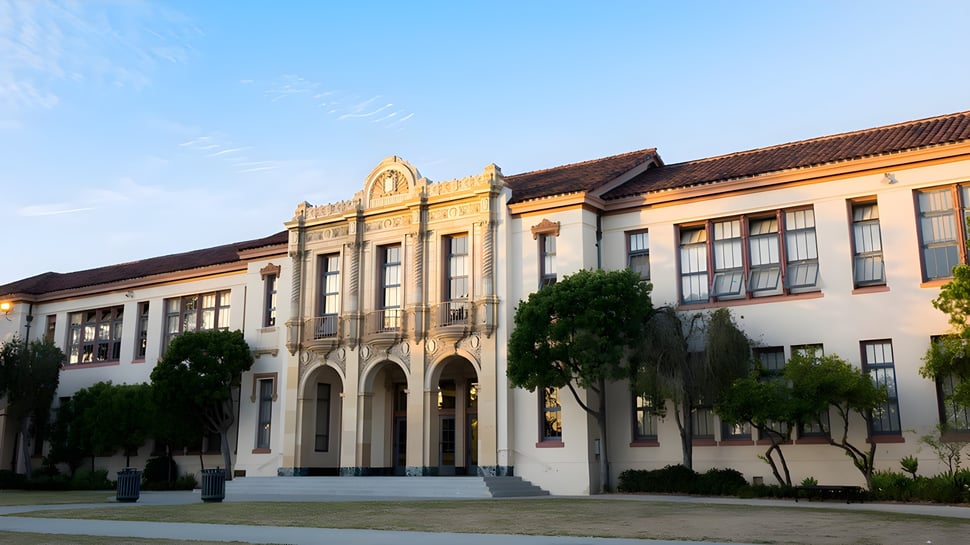 El edificio principal de la Santa Barbara High School con ventanas decoradas está incrustado en un área verde cubierta de vegetación.