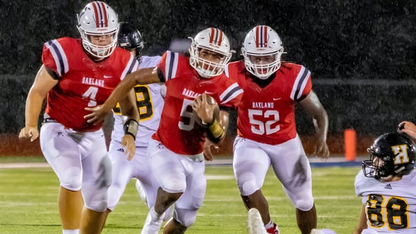 Estudiantes de la Santiam Christian School corren por el campo de fútbol durante un partido por la noche.