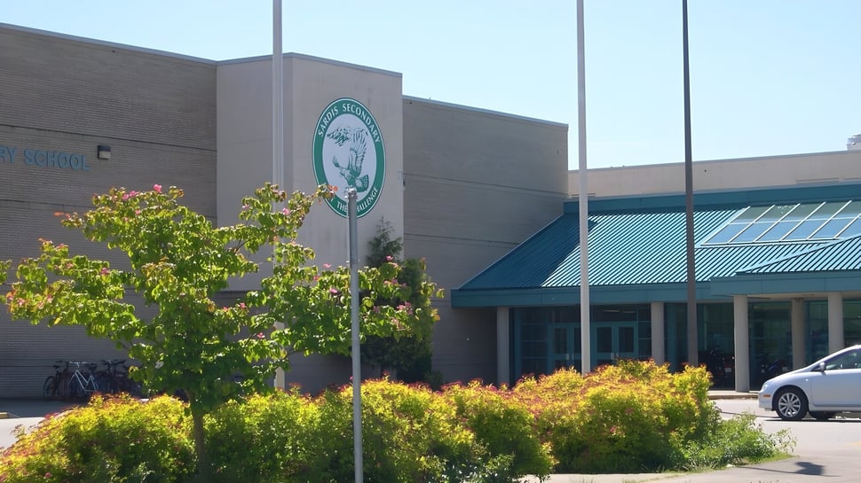 El gran edificio con el logo verde en el campus de la Sardis Secondary School está rodeado de un exuberante verde.