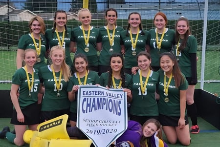 Un grupo de jóvenes futbolistas de la Sardis Secondary School posan con un banner de campeonato en el campo de fútbol.